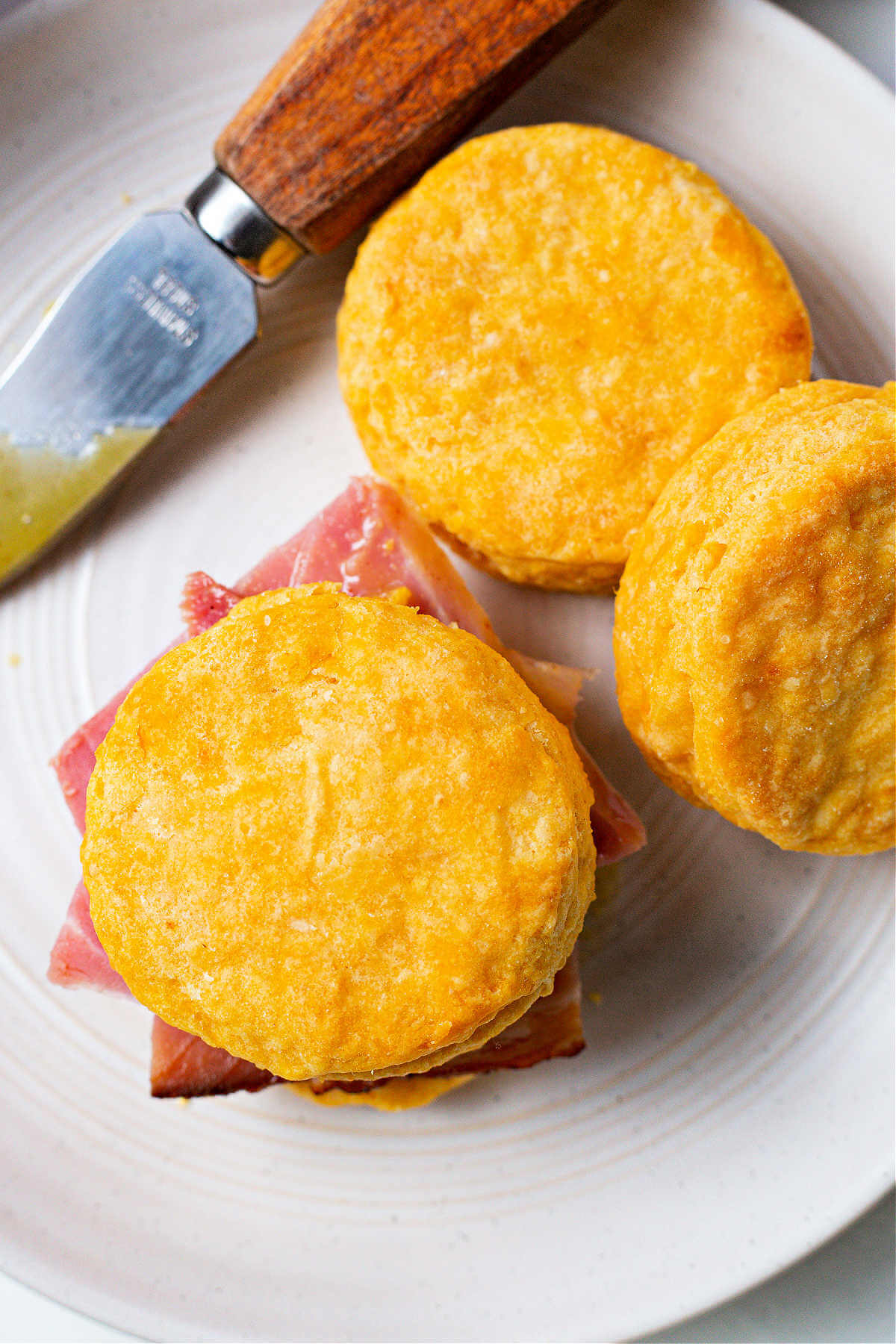 a sweet potato biscuit stuffed with ham on a plate.