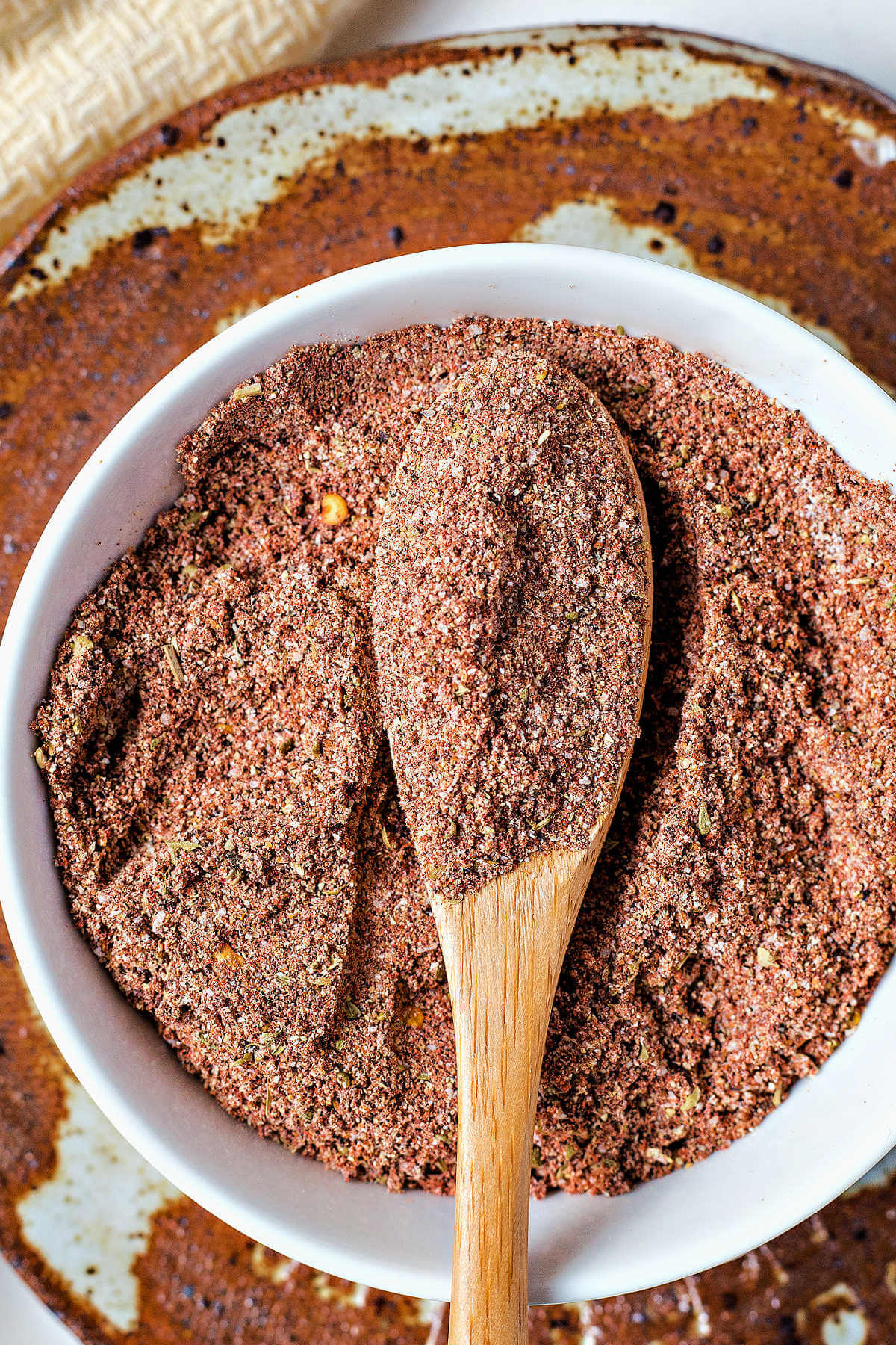 a wooden spoon in a bowl of taco seasoning and spices.