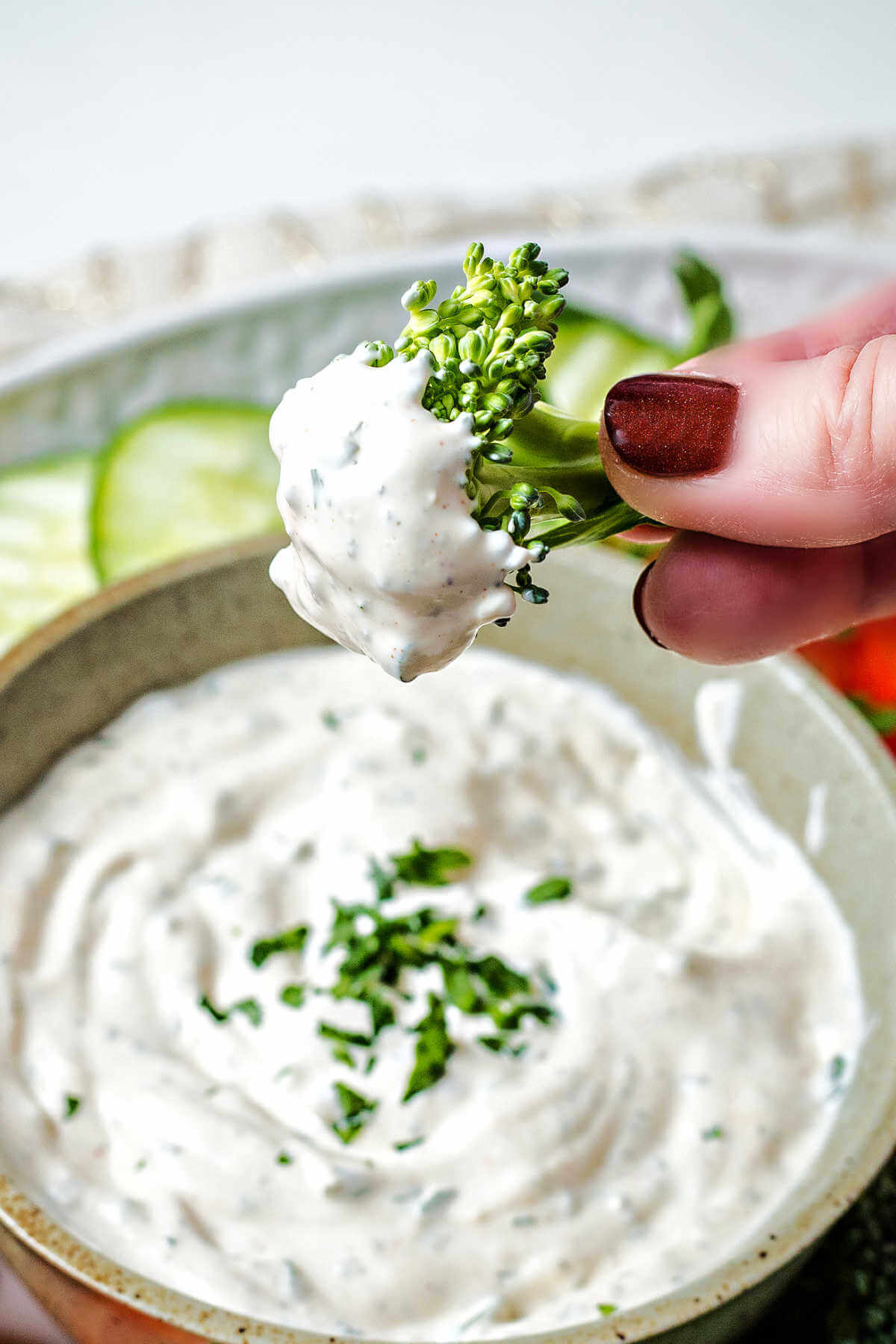 a hand holding broccoli dipped in vegetable dip.