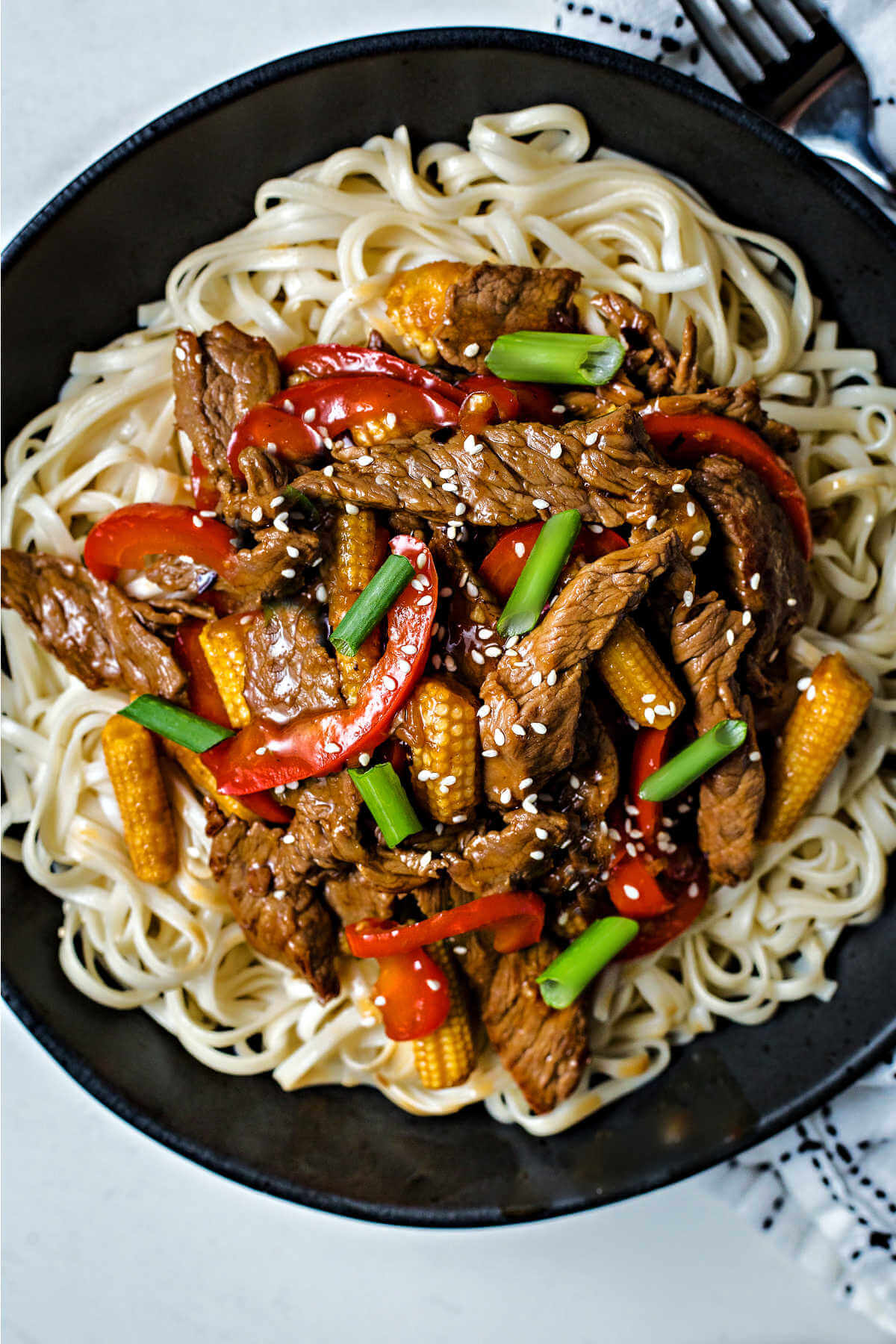 Korean Beef Stir Fry served over lo mein noodles and garnished with diced green onions and sesame seeds.