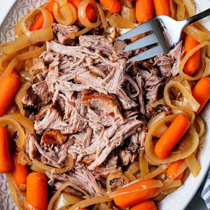 shredded pork roast on a platter with carrots.
