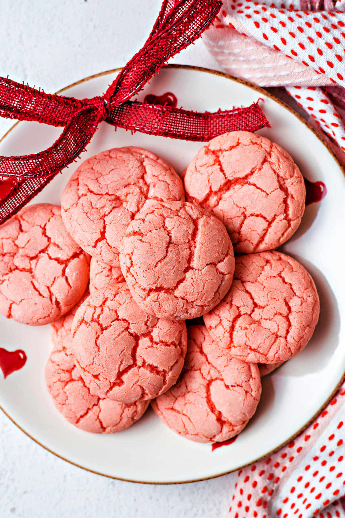 3-ingredient strawberry cake mix cookies on a valentine plate with a red ribbon on a table.