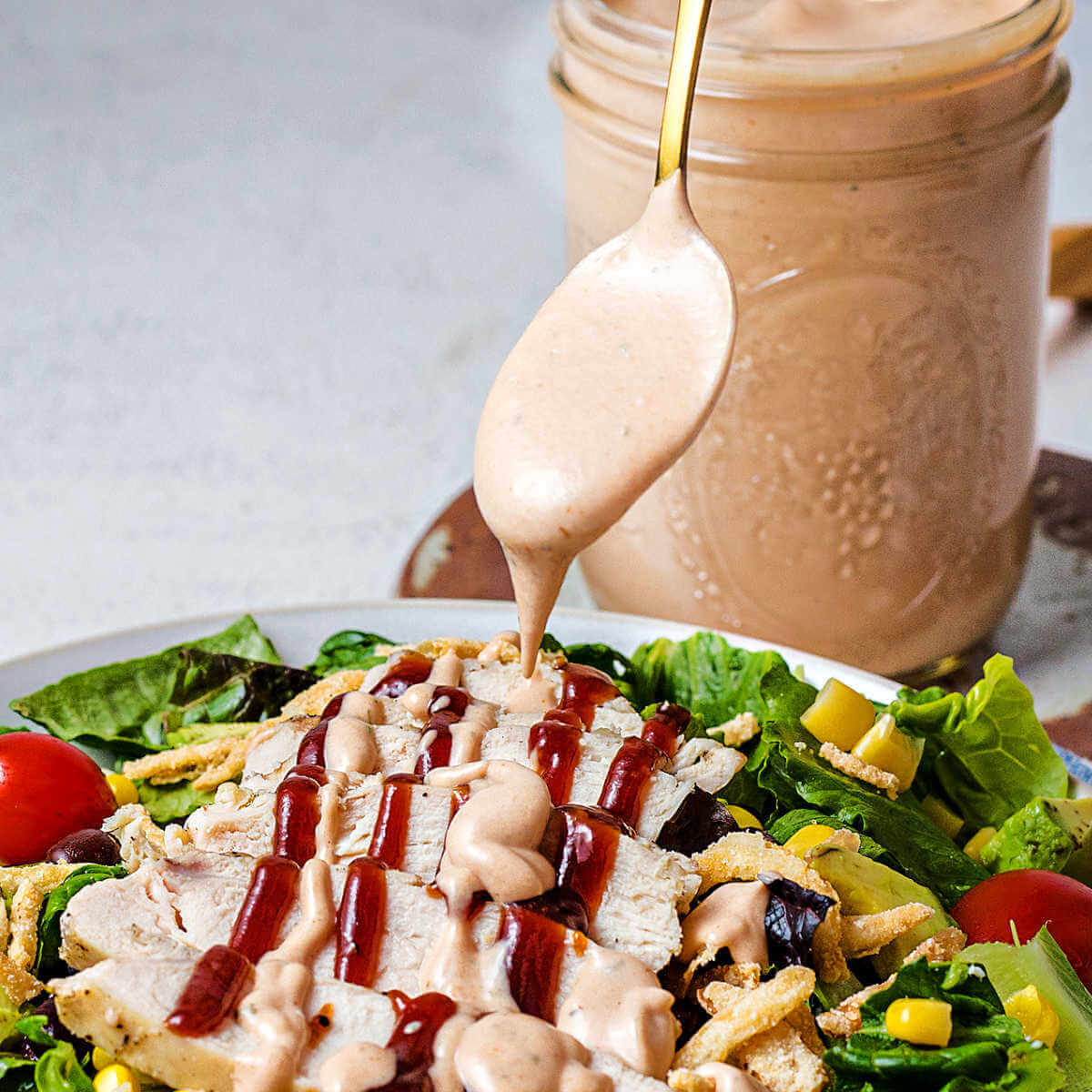 drizzling BBQ Ranch Dressing on a grilled chicken salad.