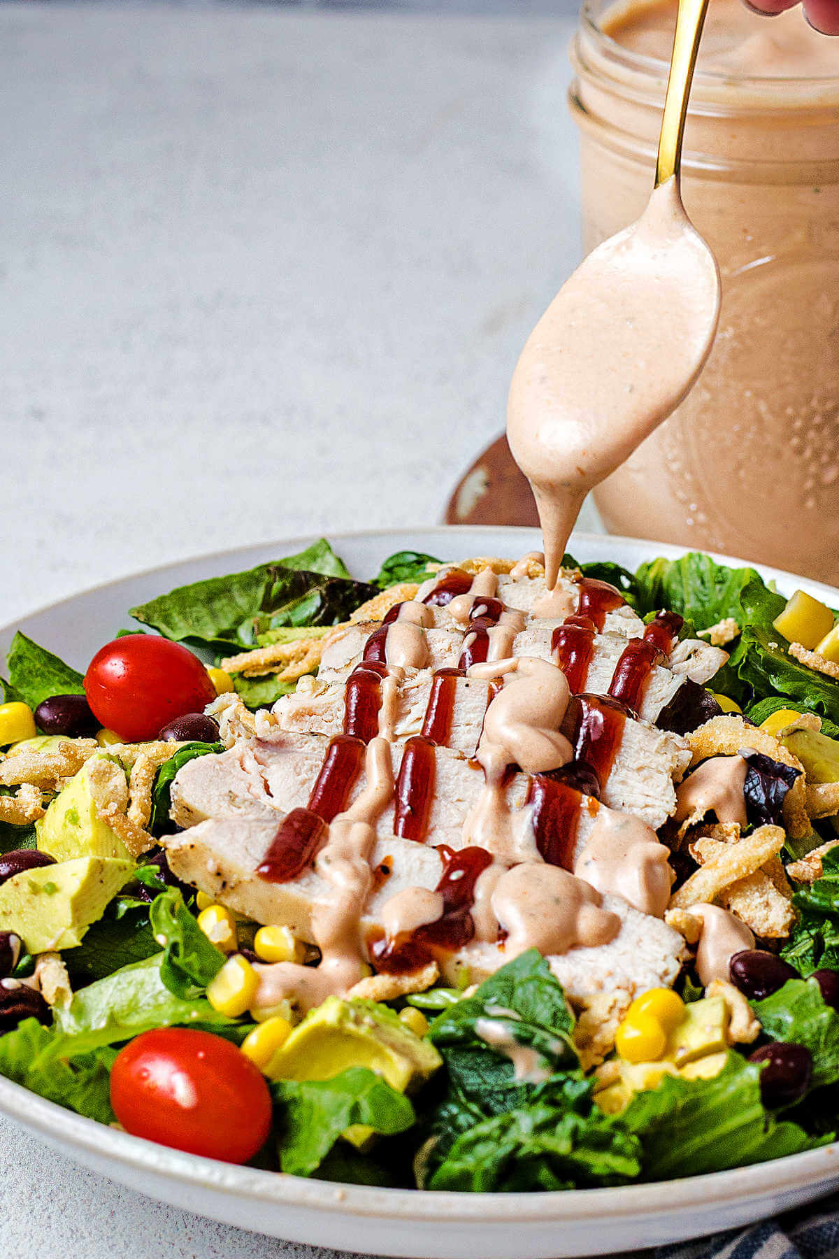 drizzling BBQ Ranch Dressing on a grilled chicken salad.
