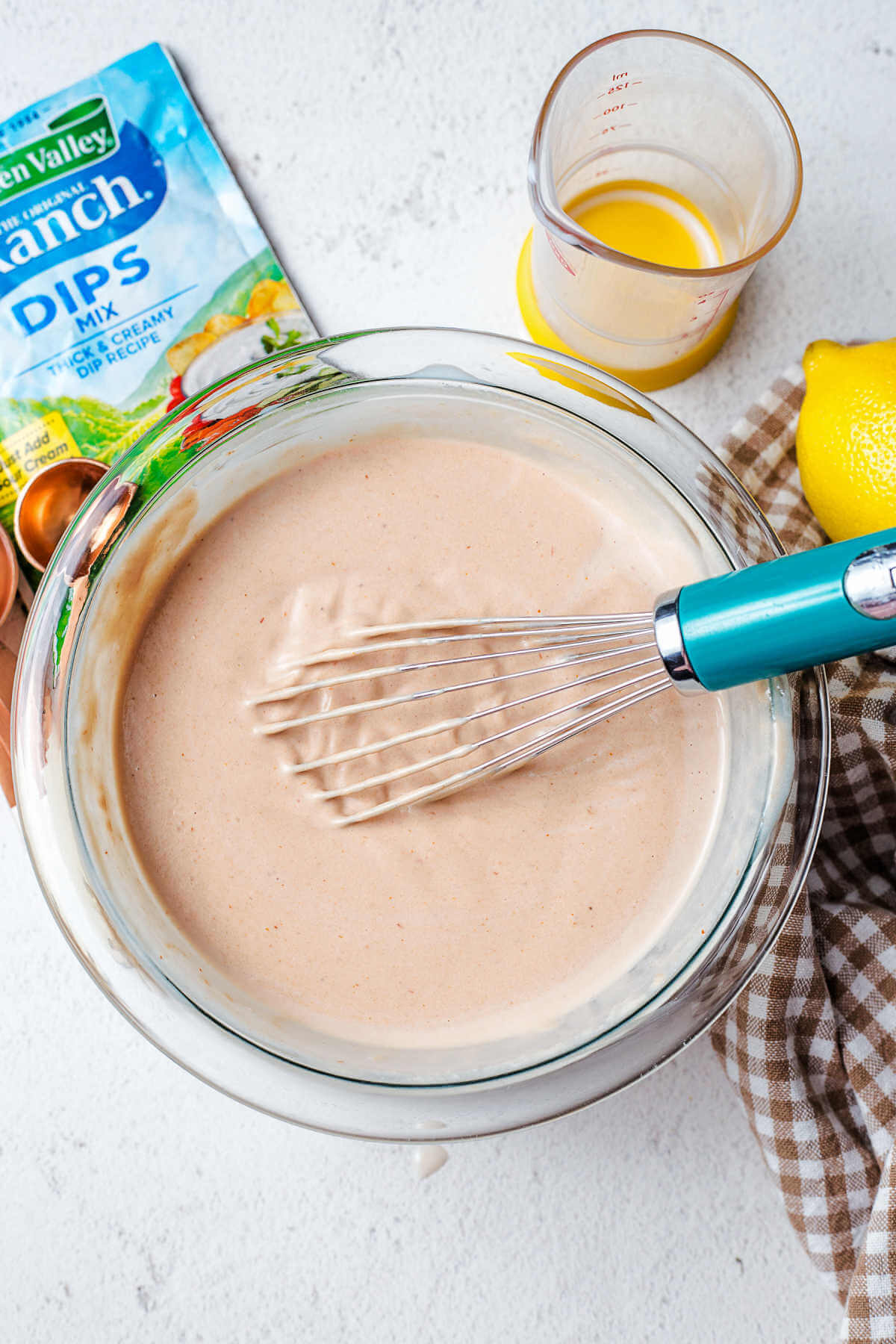 whisking together the ingredients for barbecue ranch dressing in a bowl.