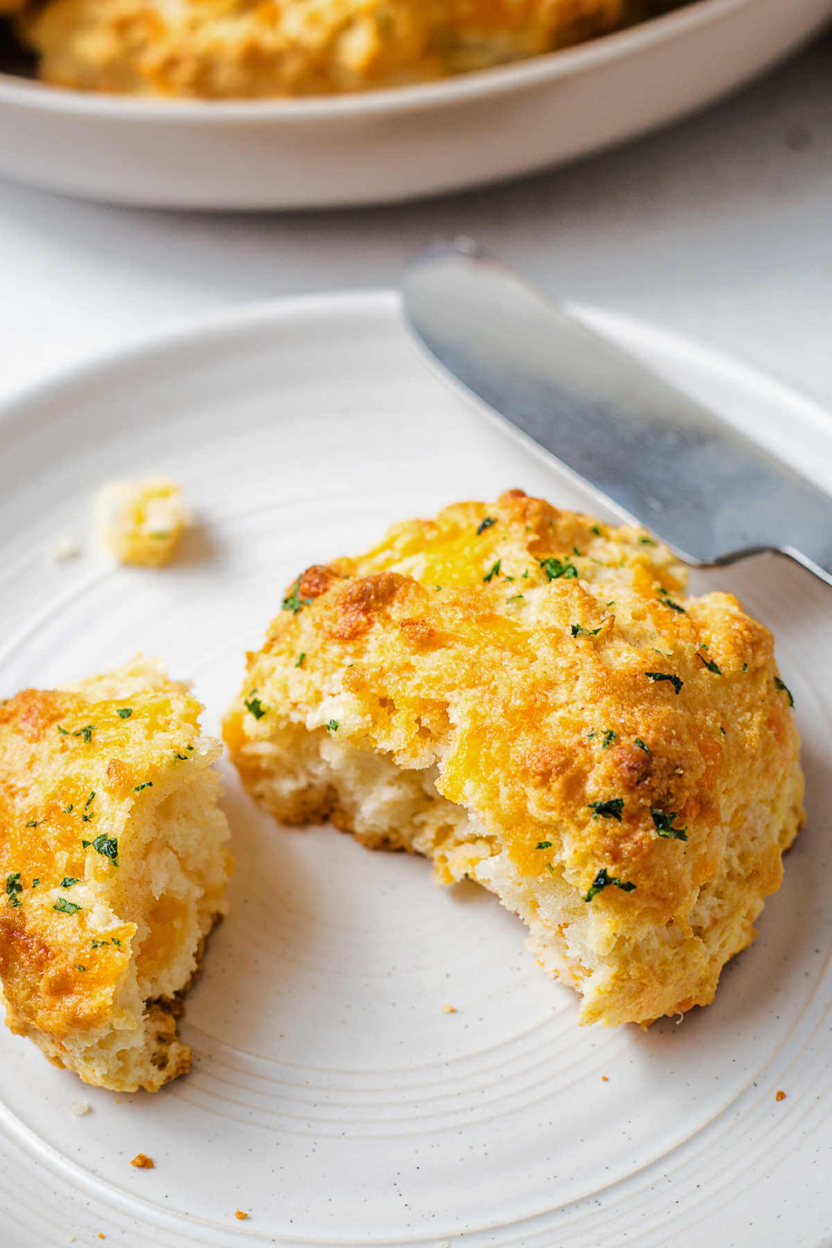 a cheddar bay biscuit broken in half on a bread plate.
