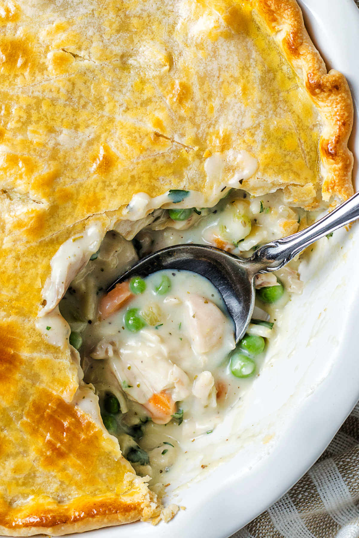 a baked Cracker Barrel chicken pot pie with a spoon inserted and a serving missing.