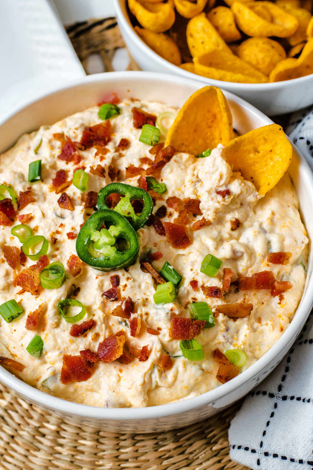 jalapeno popper cheese dip in a bowl garnished with bacon and green onions.