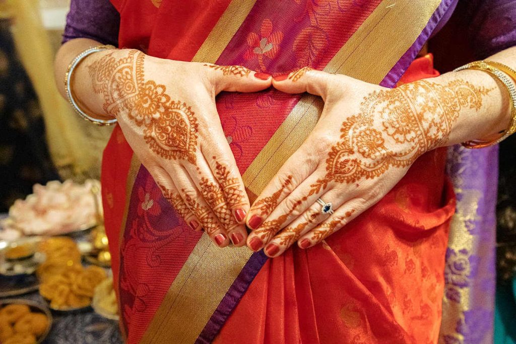 two hands decorated with henna in heart shape.