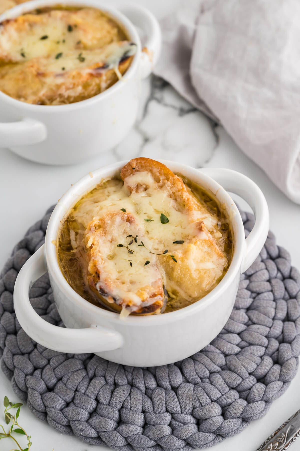 Gruyere cheese toast floating on top of French onion soup in a white bowl.