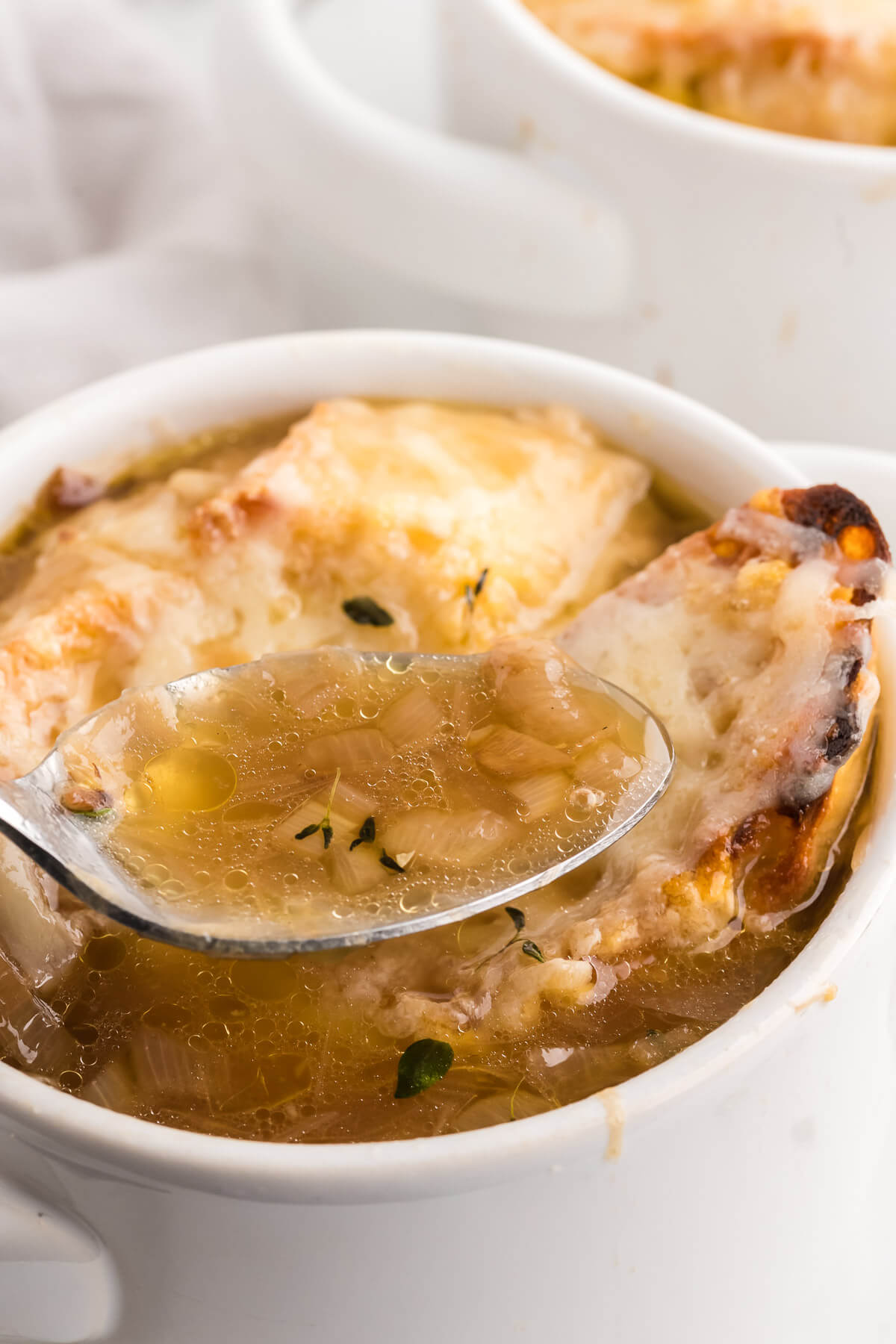a spoonful of French onion soup with rich broth and gooey cheese.