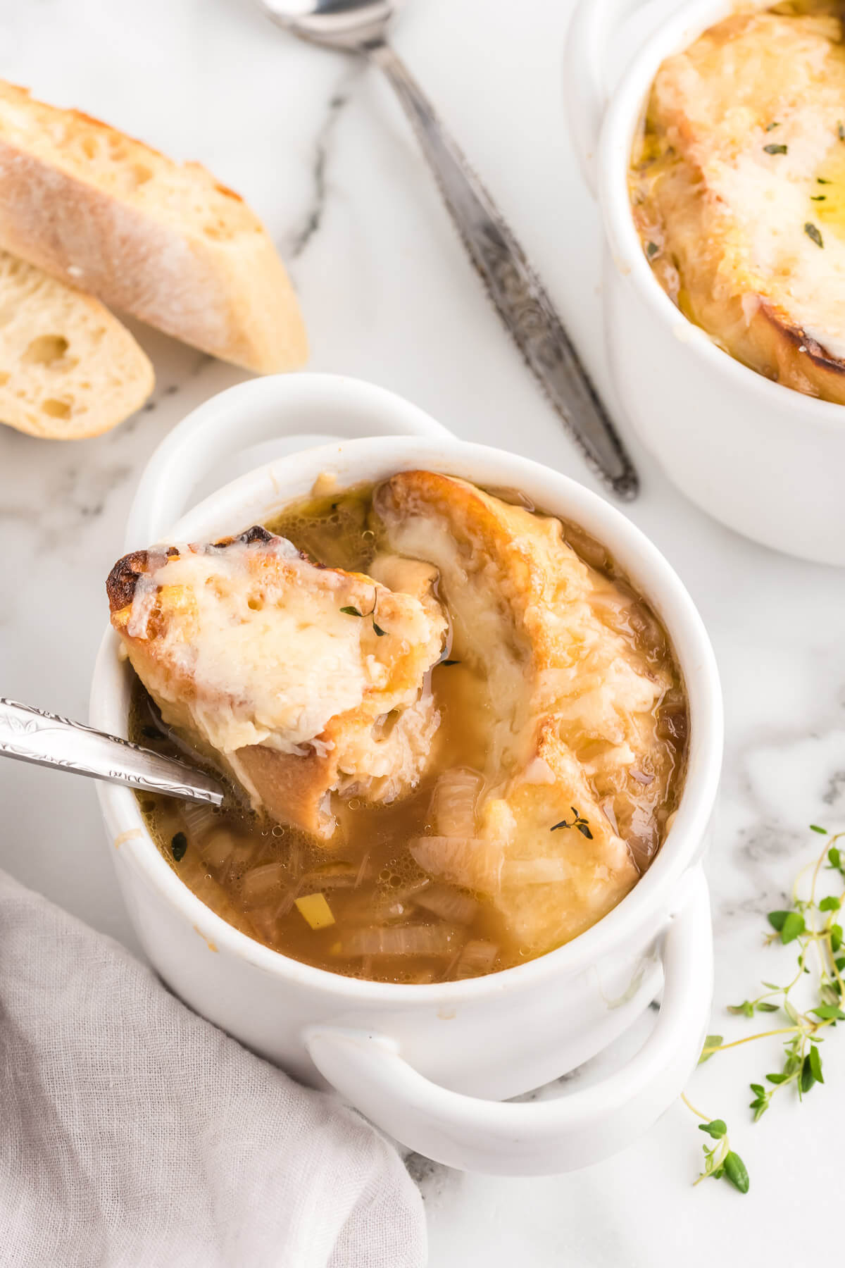 French onion soup in a soup crock with a spoon lifting out a bite of cheesy bread.