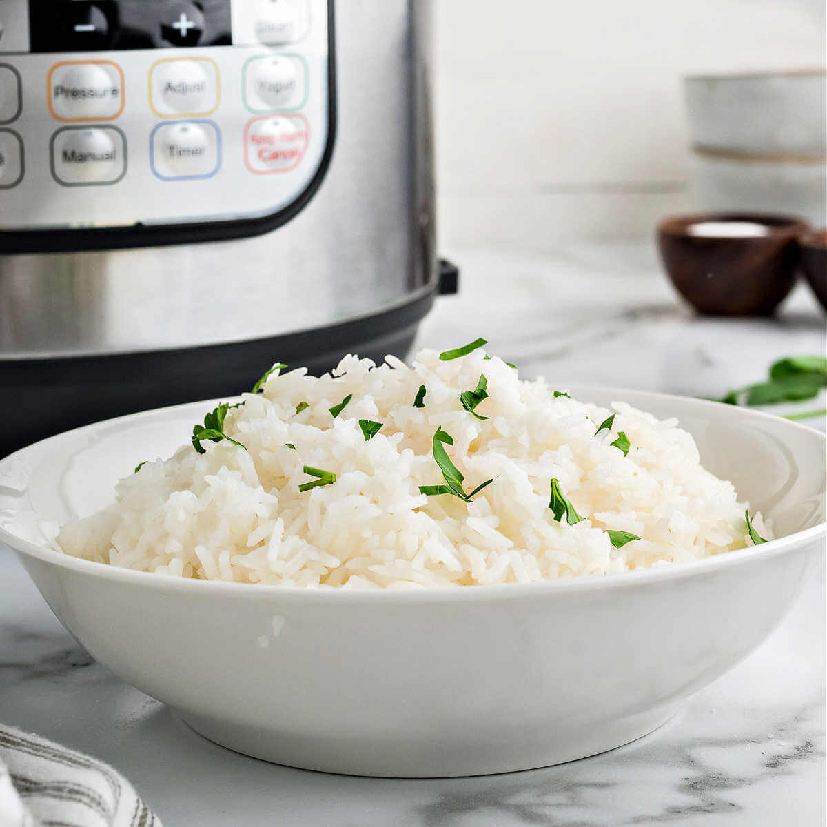 a bowl of jasmine rice on a table with an instant pot in the background.