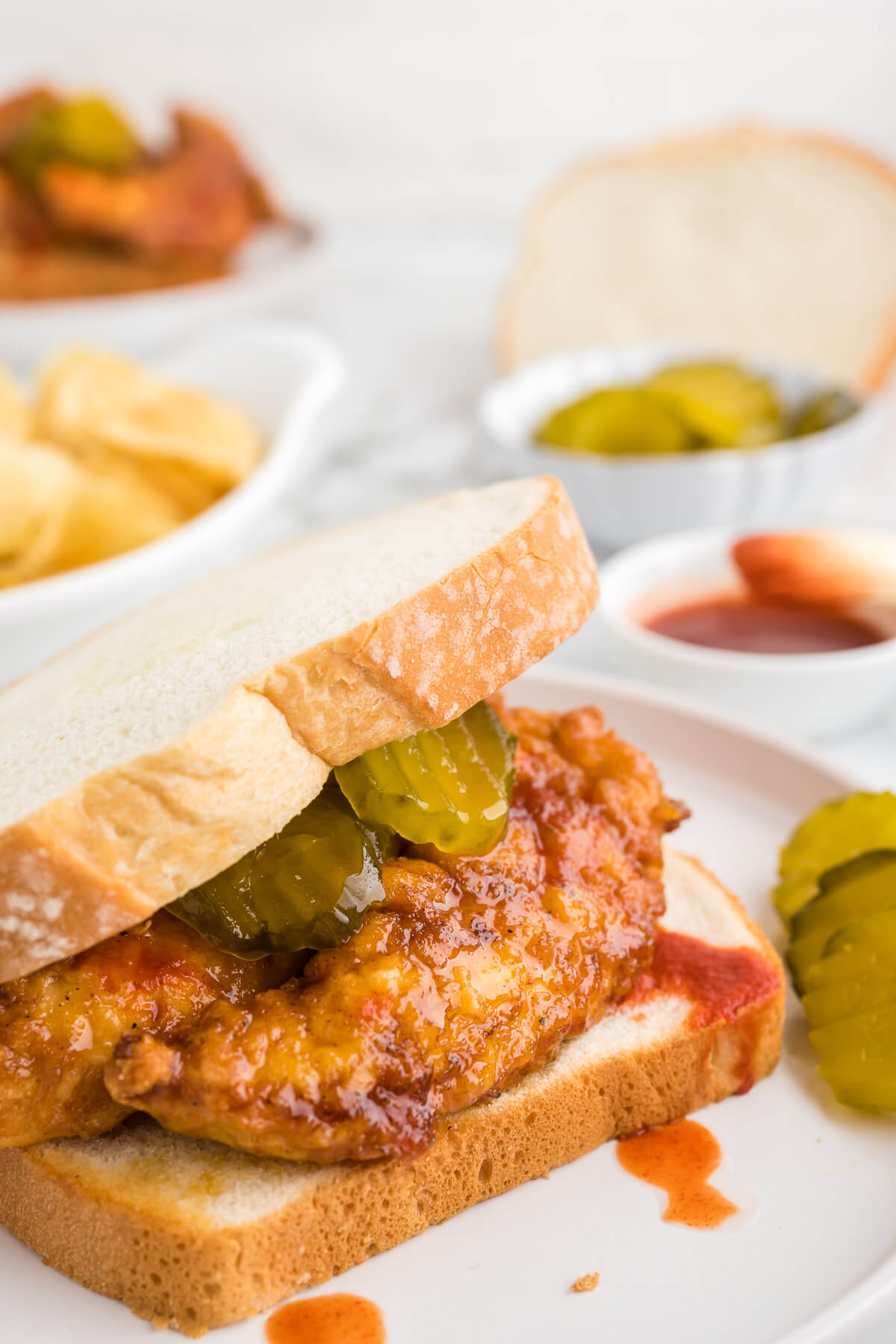 Nashville-Style Hot Chicken Sandwich on a plate with hot sauce drizzled on top.