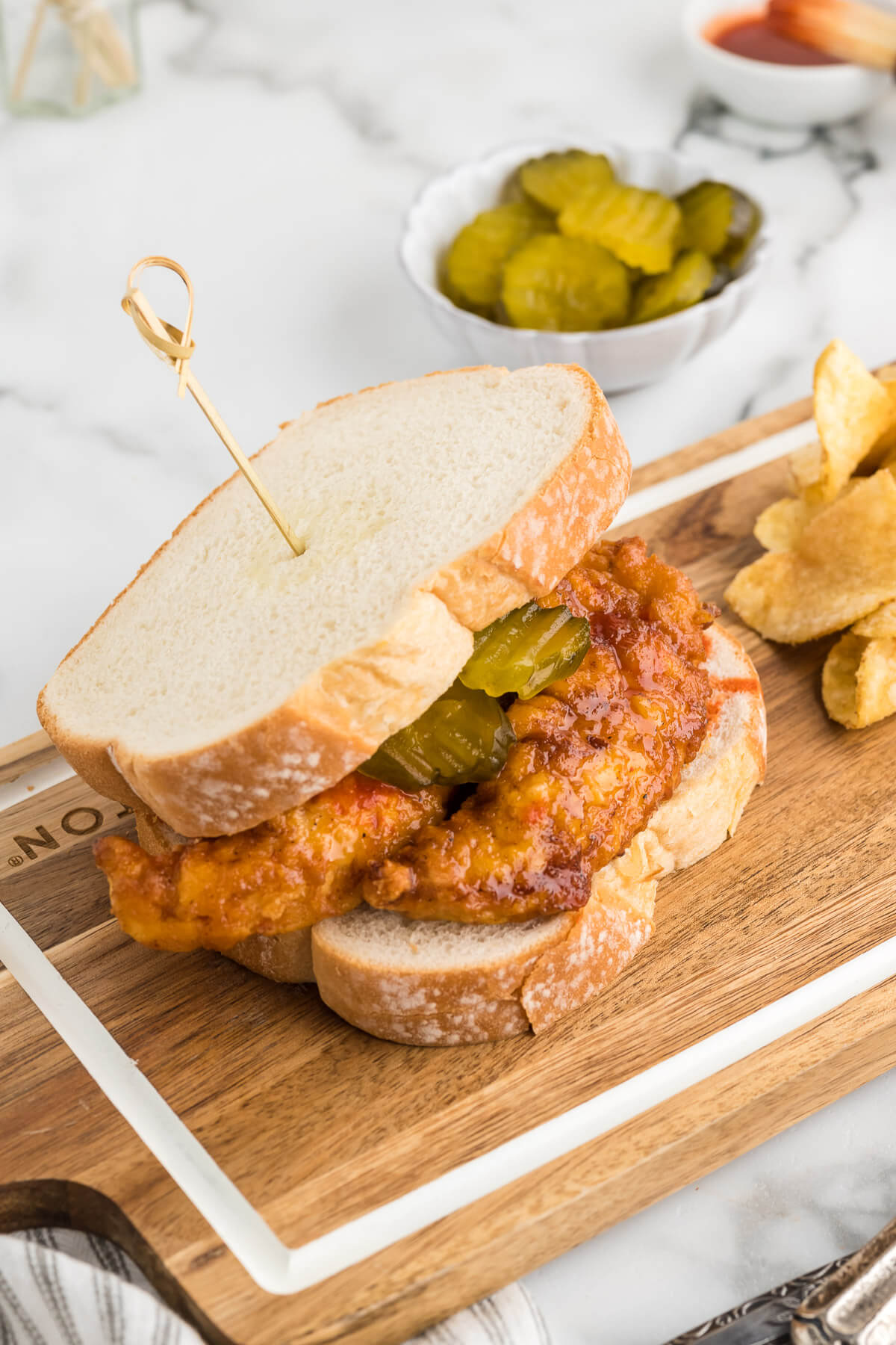 Nashville Style Hot Chicken Sandwich on a wooden board on a table.