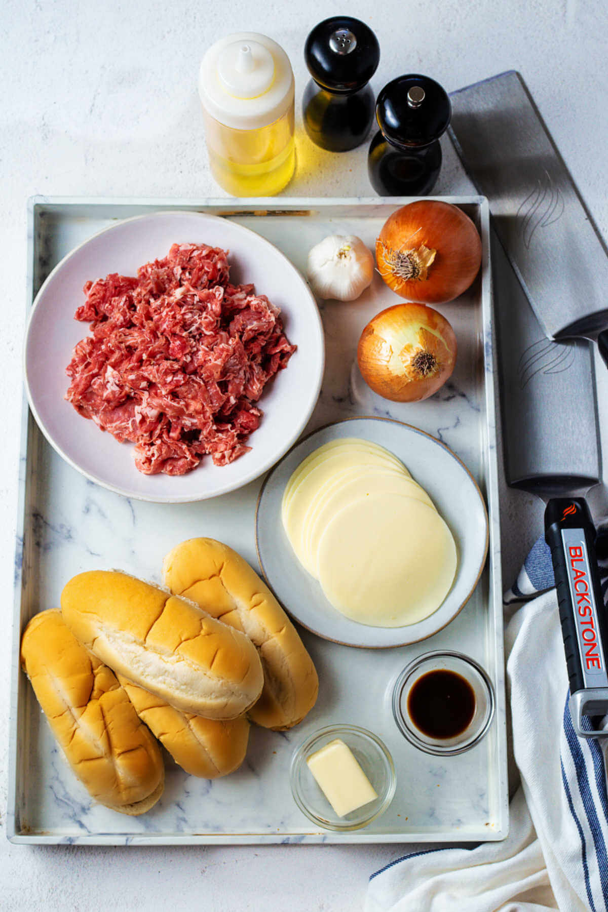 ingredients for Philly cheesesteak on a table with Blackstone spatulas.