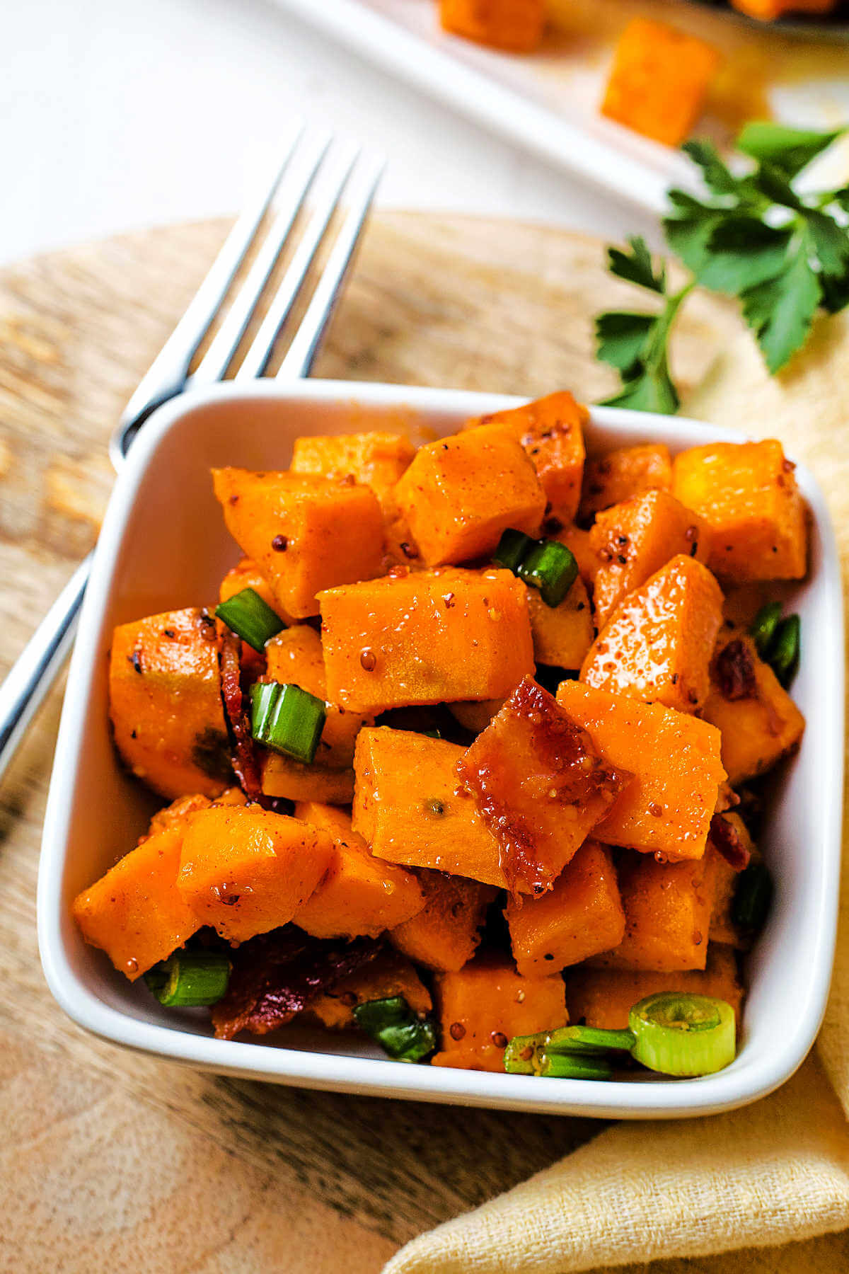 a serving of sweet potato salad in a small white bowl on a table.
