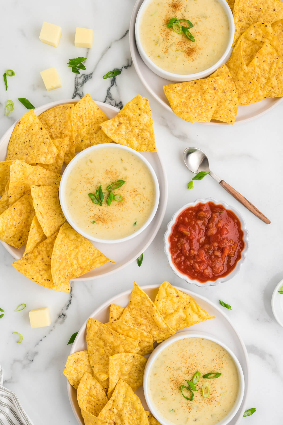 individual servings of white queso dip and chips on a table.