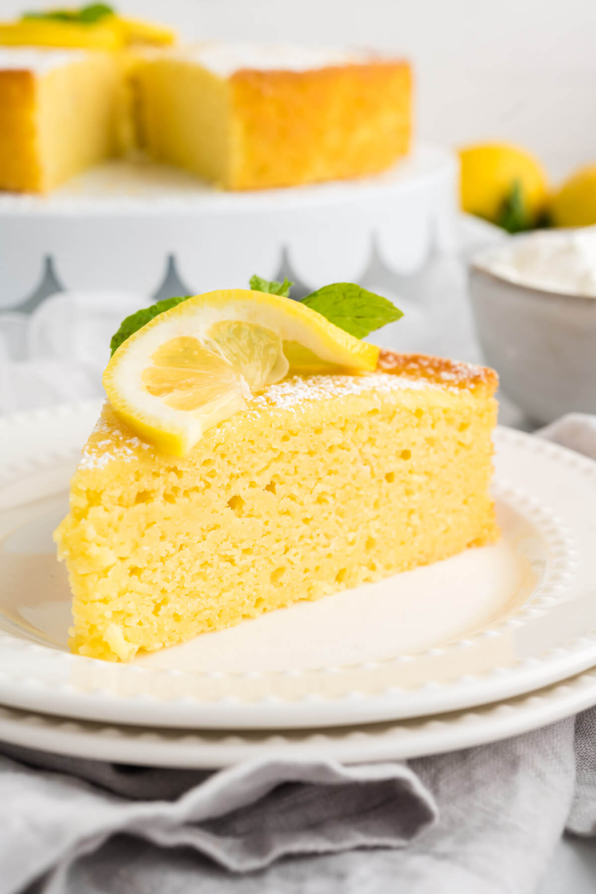 lemon ricotta cake garnished with a lemon slice and mint sprig.