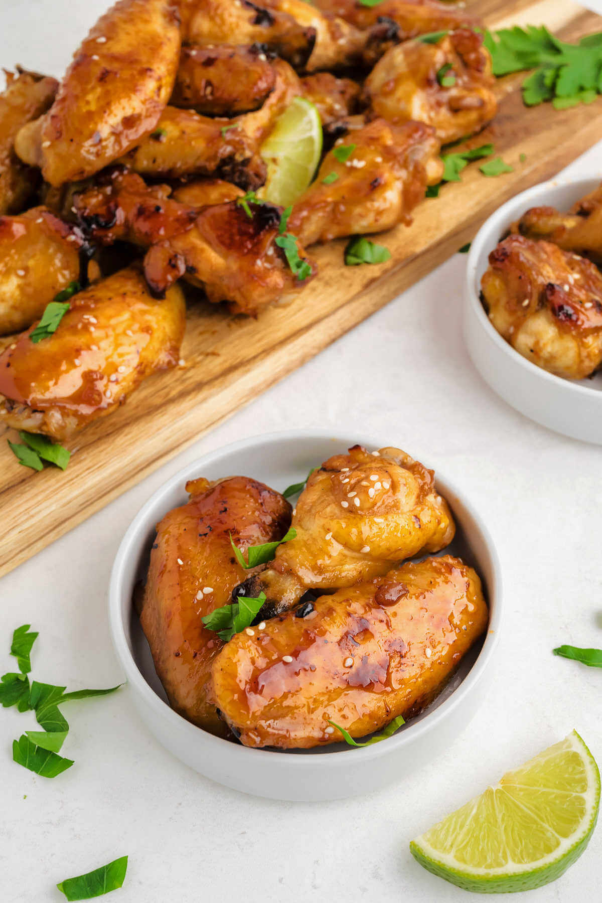 a serving of chicken wings in a bowl with lime wedges.