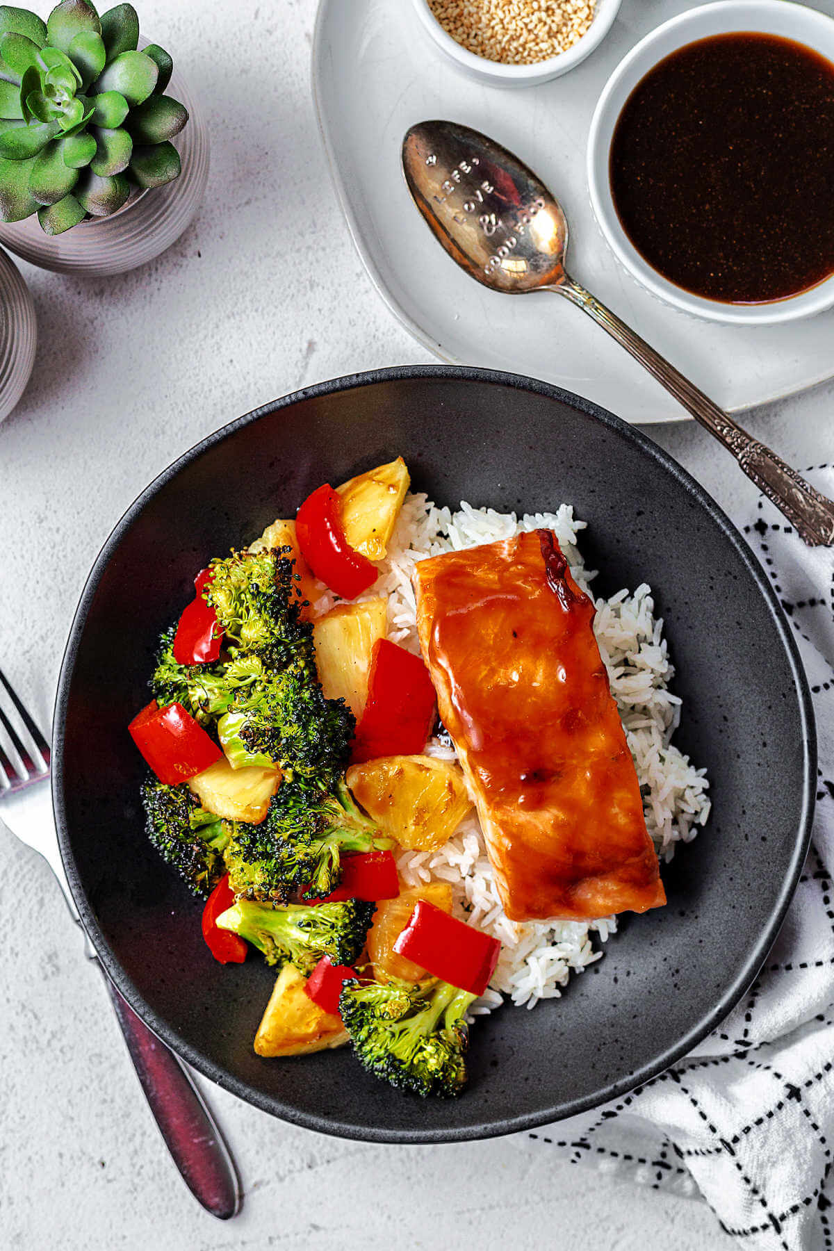 salmon bowl on a table with small bowls of condiments to the side.