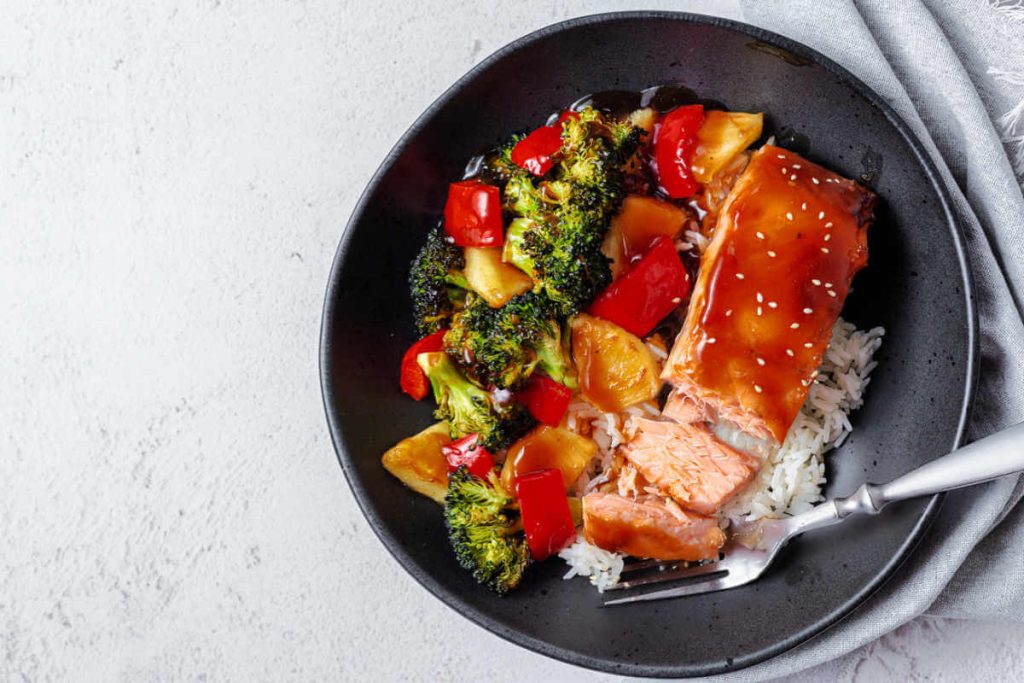 salmon bowl with homemade teriyaki on a table with a linen napkin and fork.