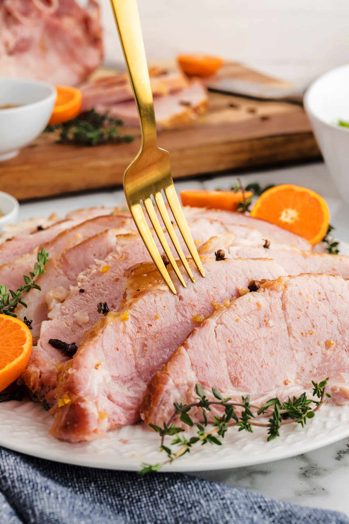 a fork piercing a slice of orange glazed ham.