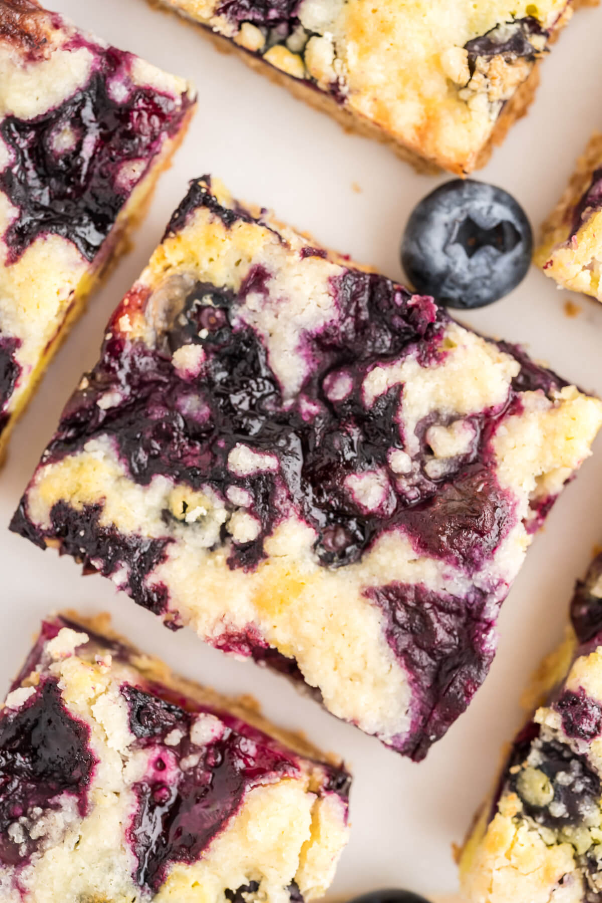 sliced blueberry crumb bars with fresh blueberries scattered between.