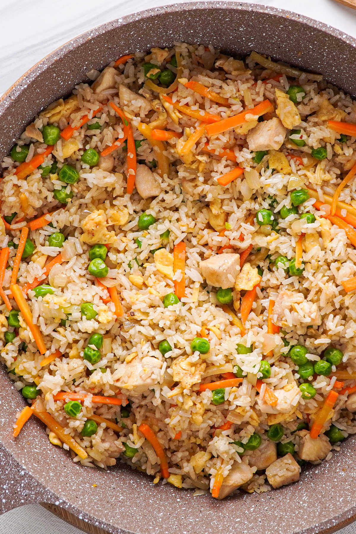 close up shot of fried rice in a wok with chicken.