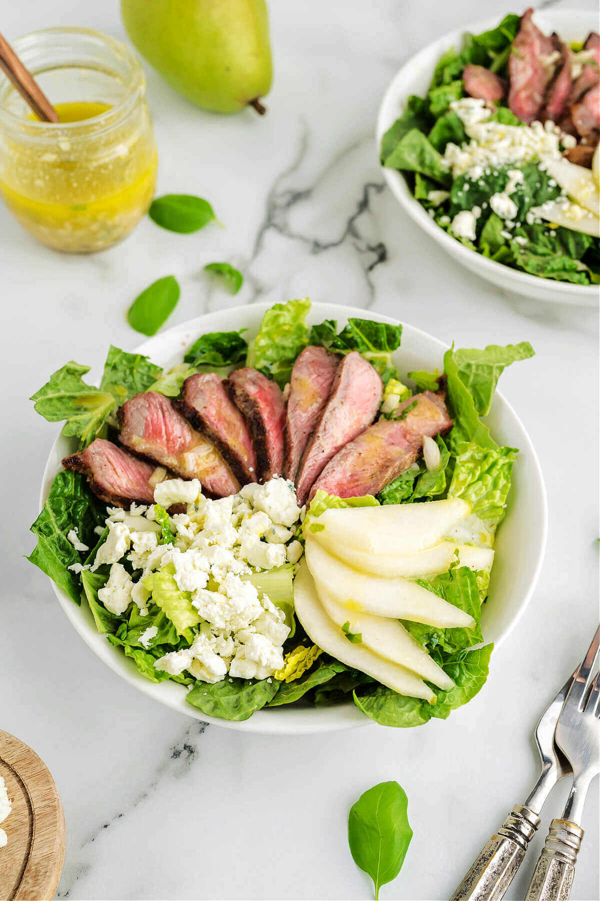 a bowl of grilled steak salad with condiments on a table.
