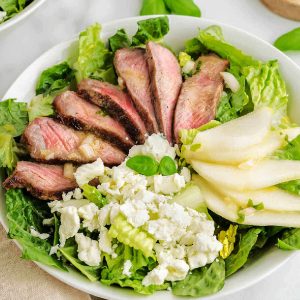 Grilled Steak Salad with a French Vinaigrette in a white bowl on a table.