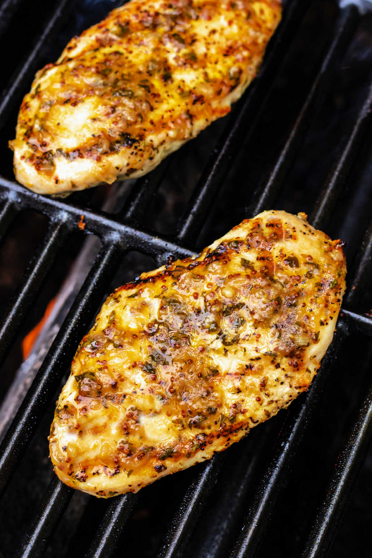 Italian style grilled boneless chicken breast cooking on a gas grill.