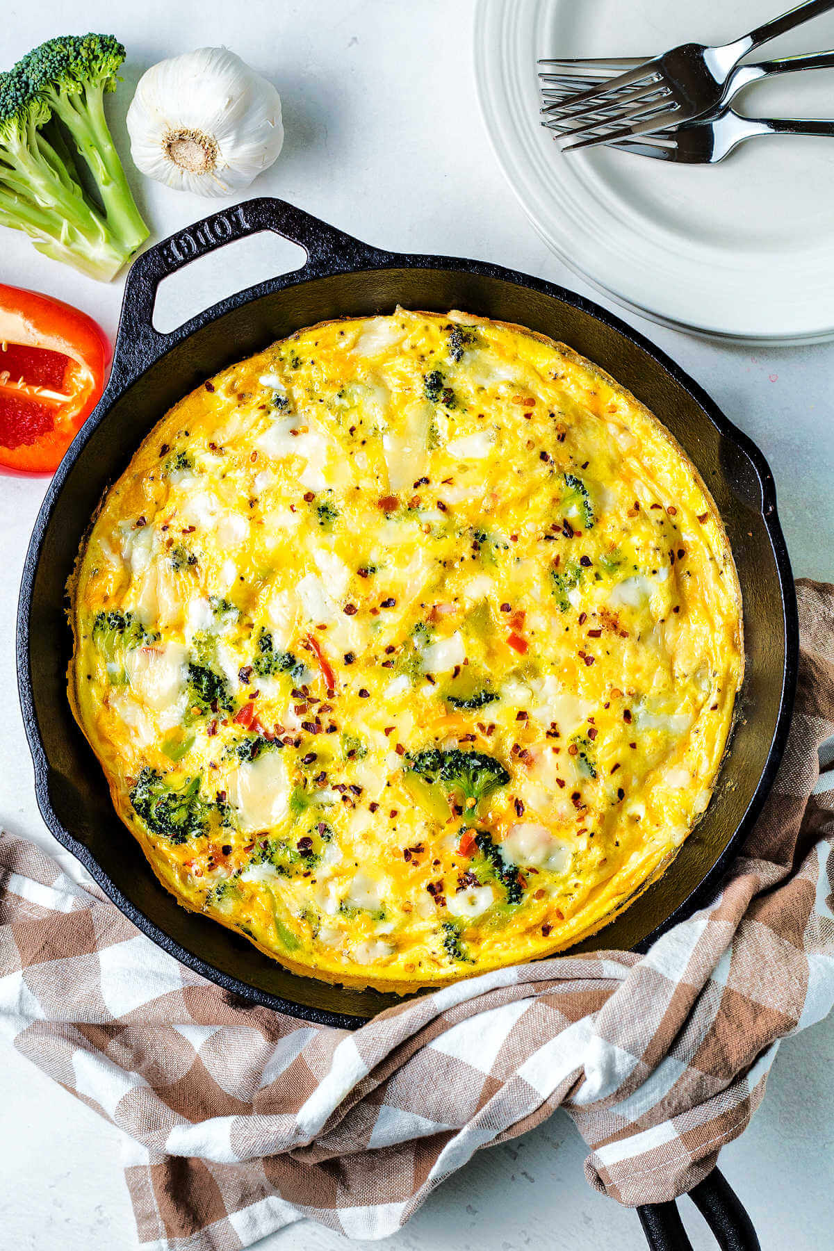 baked vegetable frittata on a table with plates and forks.