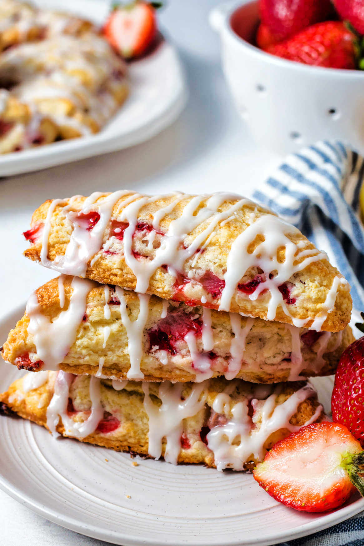 fresh strawberry scones stacked on top of each other on a plate on a table.