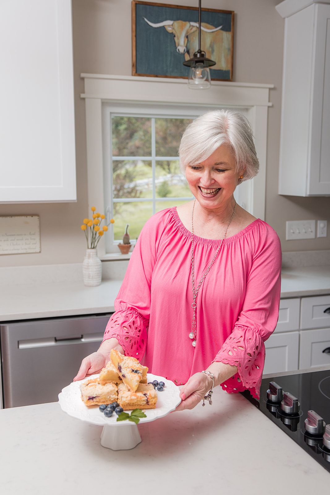 Sheila Thigpen with a plate of blueberry bars in a white kitchen.