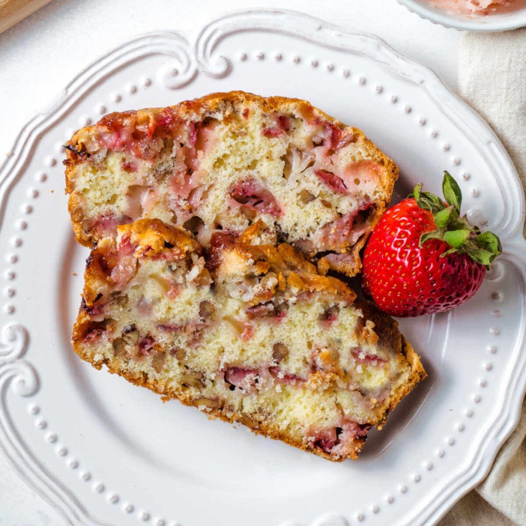 two slices of fresh strawberry bread on a white plate on a table.