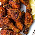 air fryer chicken legs piled high on a white platter.