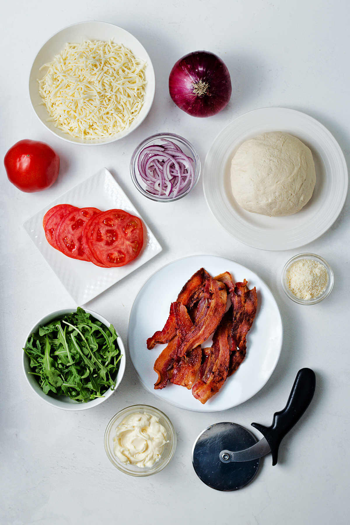 ingredients for BLT pizza on a table.