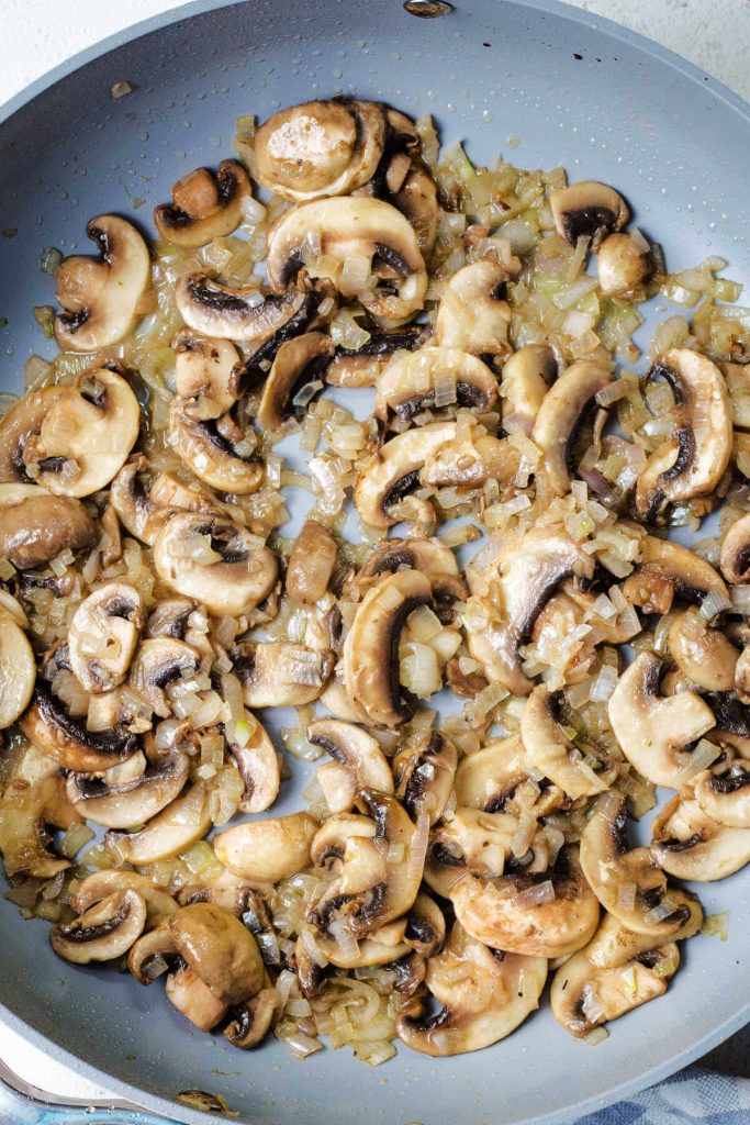 sliced mushrooms cooking in a pan for gravy.