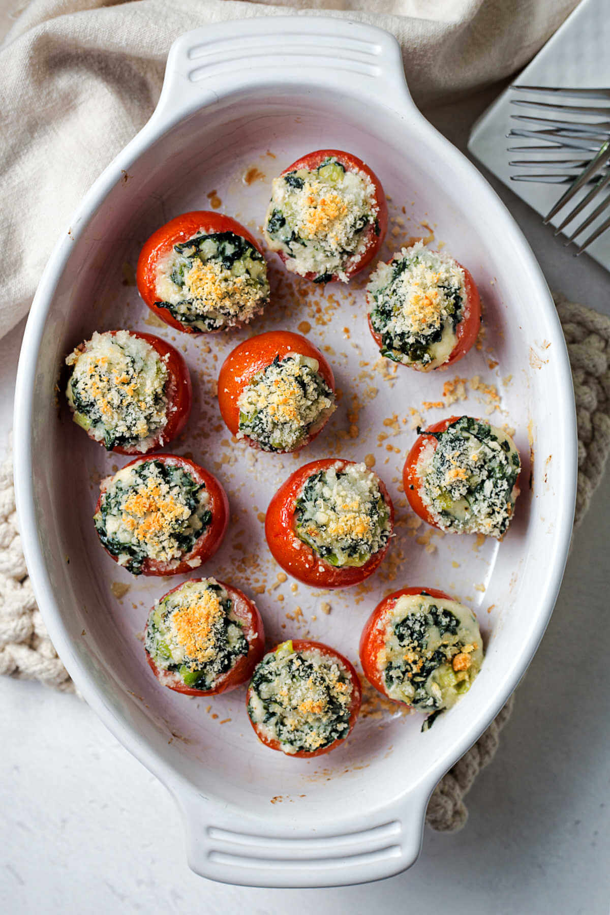 spinach stuffed baked tomatoes in a baking dish straight from the oven.