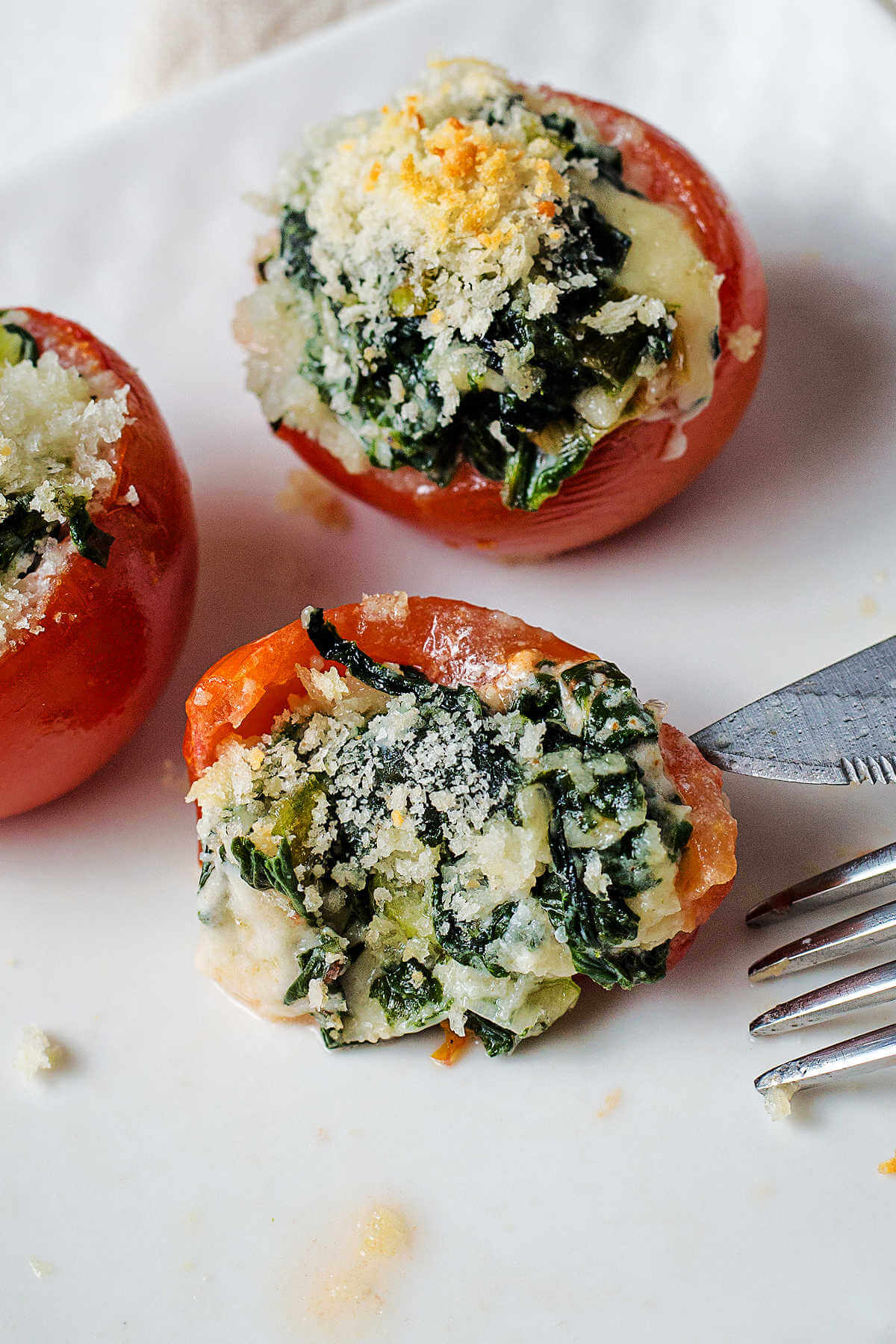 a spinach stuffed baked tomato cut in half on a plate.