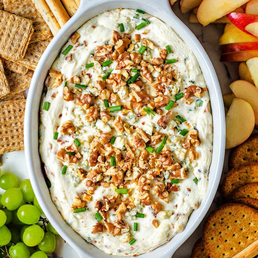 Blue Cheese Dip with Bacon, Chives, and Walnuts on a tray with crackers and fruit.