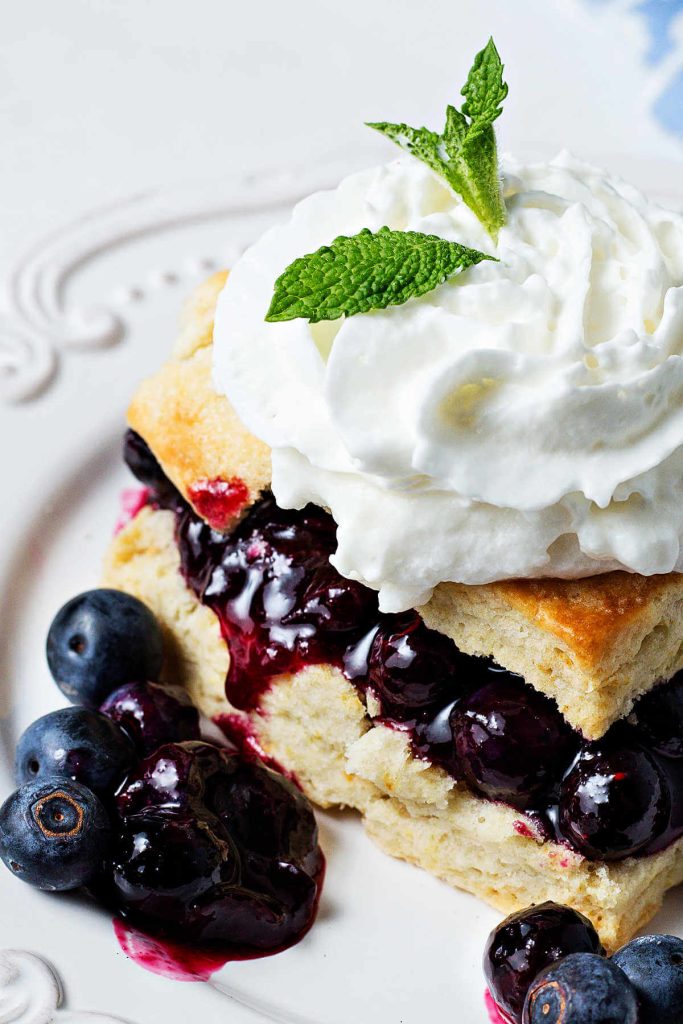 close up of a blueberry shortcake with whipped cream on a plate.