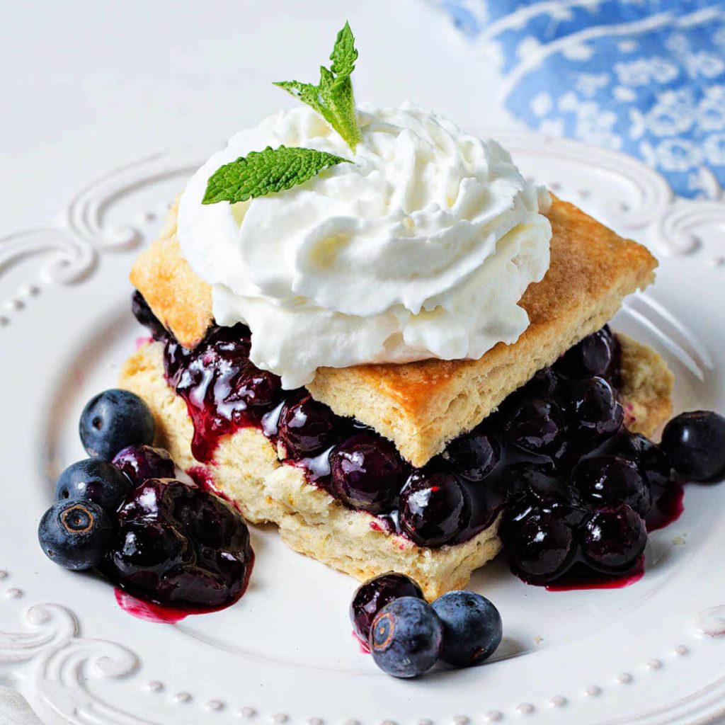 blueberry shortcake with whipped cream on a plate.