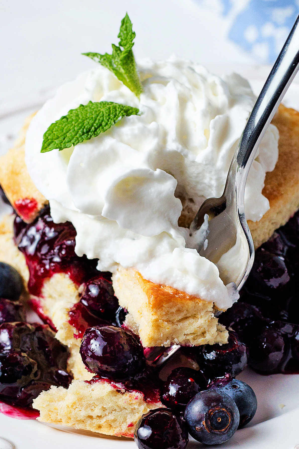 a fork cutting into a blueberry shortcake dessert on a plate.
