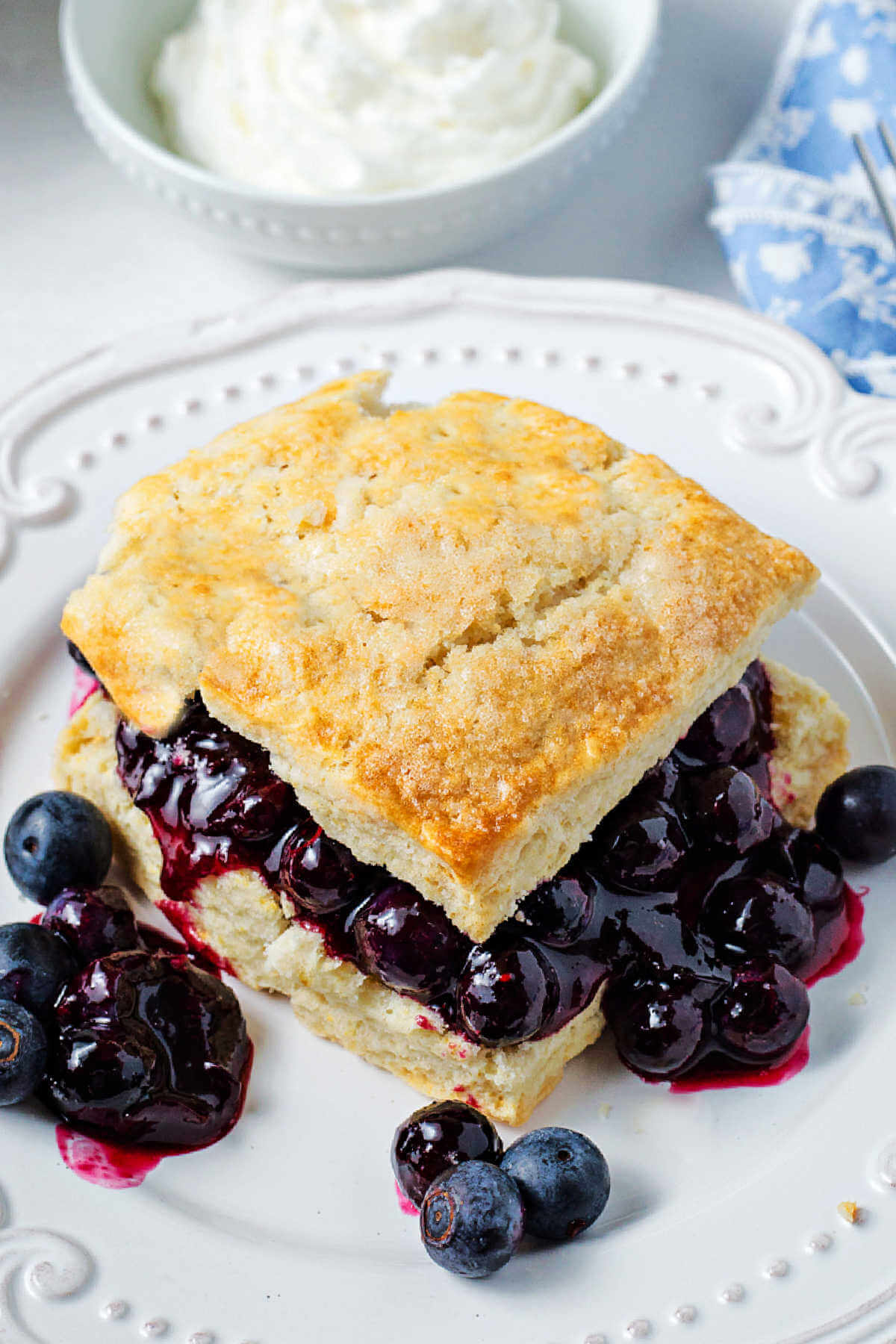 a shortcake split open and covered with blueberries on a plate.