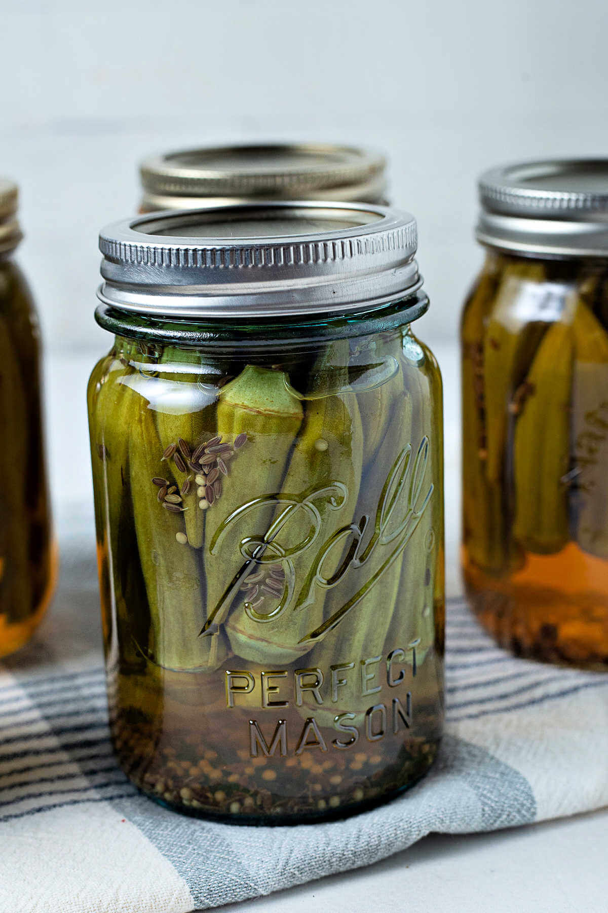 a pint jar of pickled okra sitting on a kitchen towel.