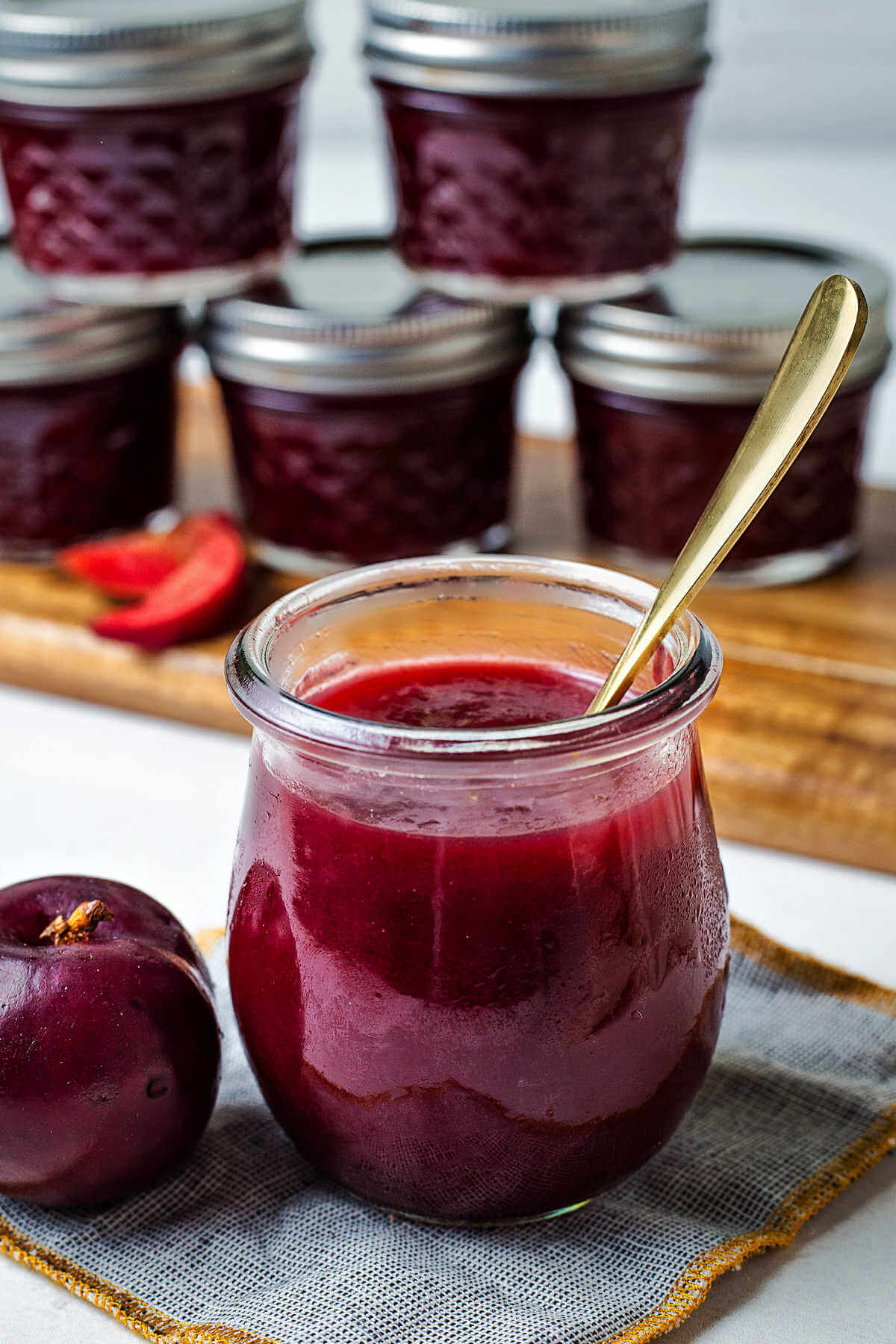 jars of plum jam stacked on a table.