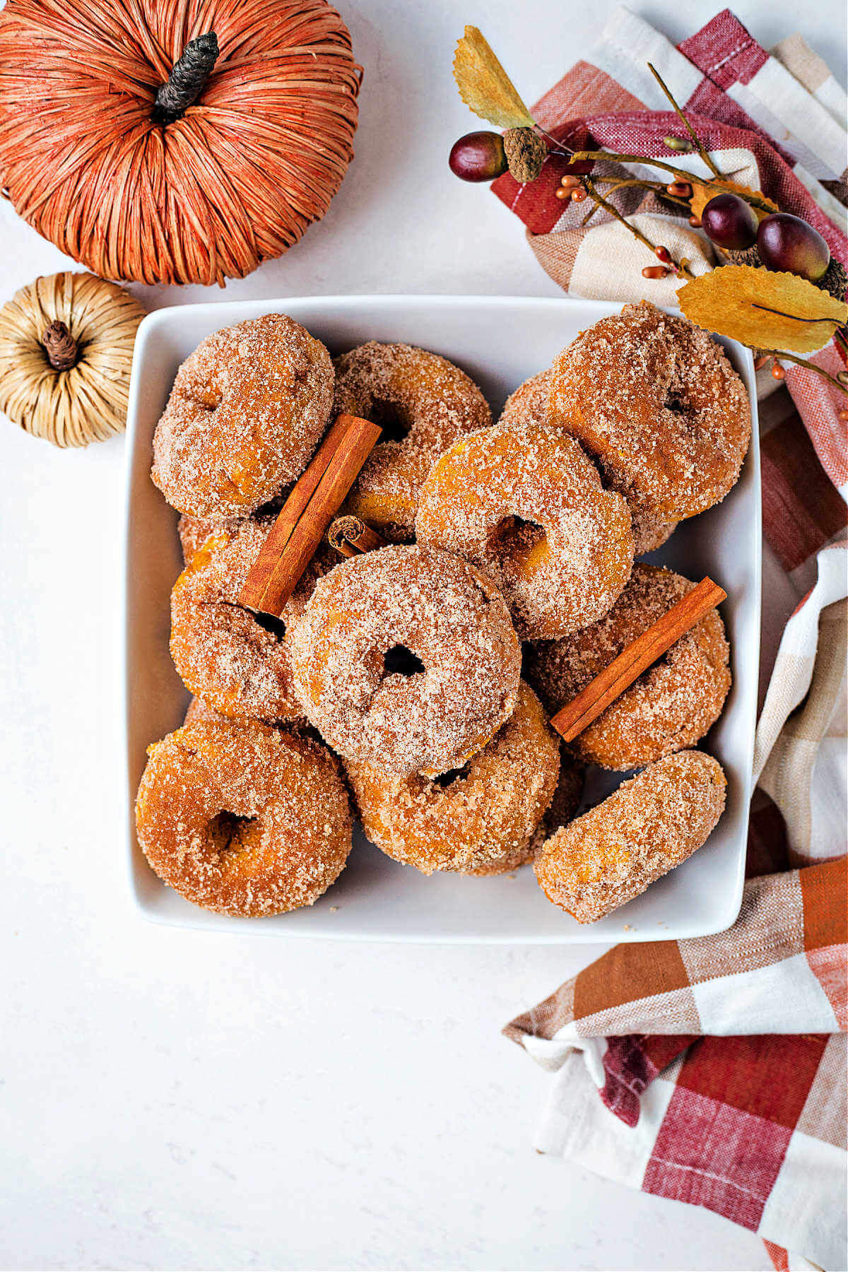 baked pumpkin donuts in a bowl on a table with festive decor.