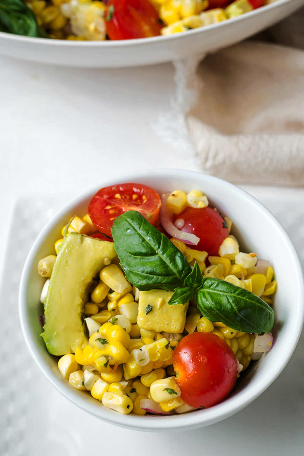 a serving of corn and avocado salad in a bowl on a table.